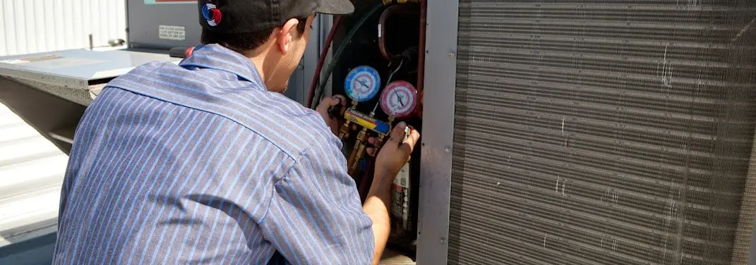 HVAC technician servicing a condenser unit in Morrilton